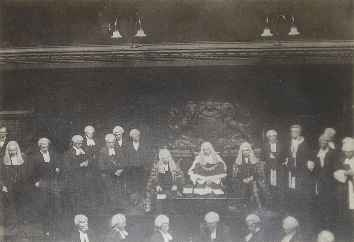 Image of Interior of Court Room with Three Seated Judges and Numerous Attendants