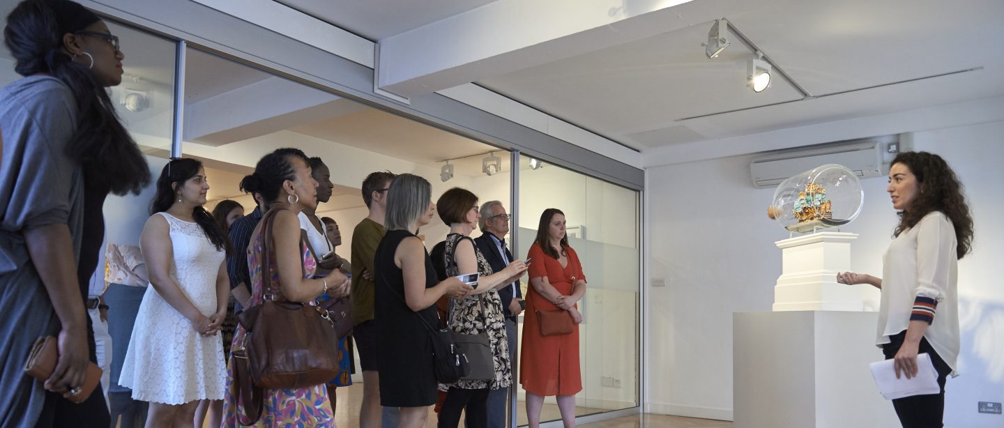 A curator gives a tour of the gallery to a group of visitors