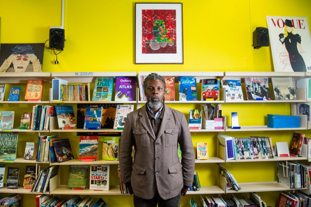An artist standing in front of his work in a library