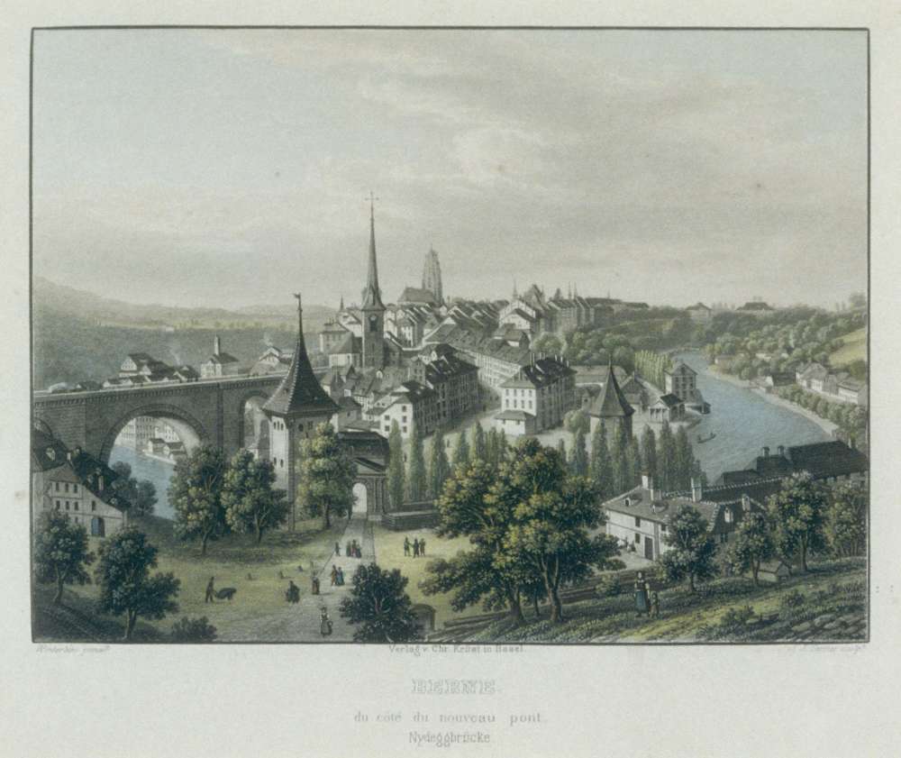 A view from a hill of a picturesque city; a bridge overlooks a wide river, turrets sit on top of many of the buildings and people can be seen wandering around the surrounding valley.