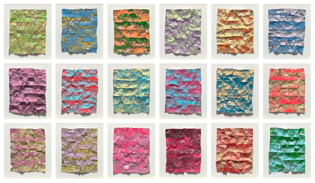 A series of 18 artworks in rows of three; each artwork is a piece of foil scrunched up in different colours.