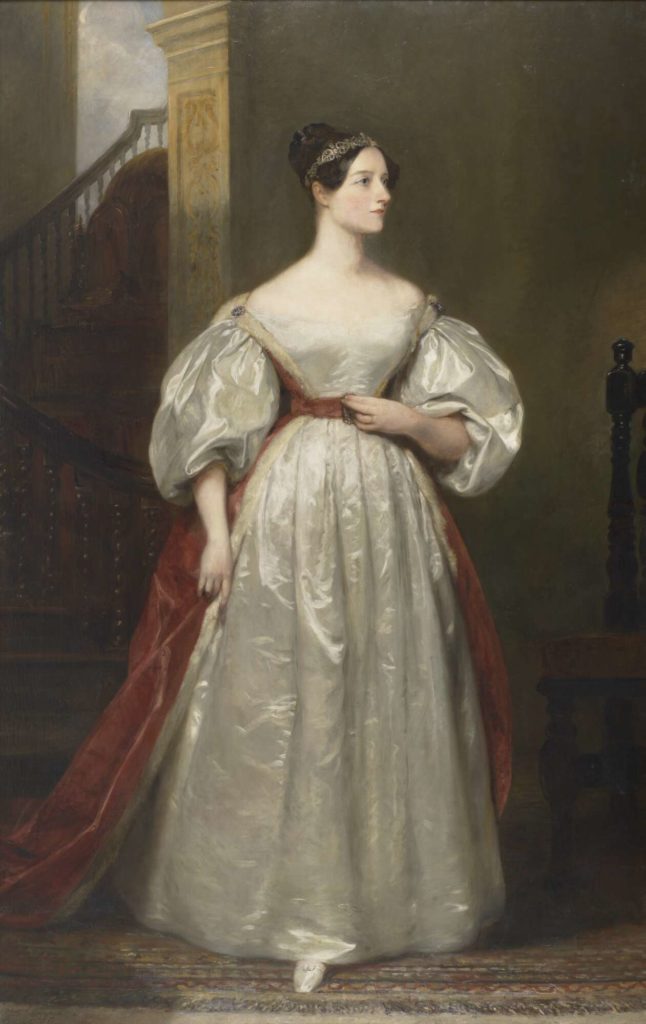 Portrait of a white woman in a white flowing dress in a dark room with a staircase behind her. She is wearing a red sash around her waist and is looking to the right.